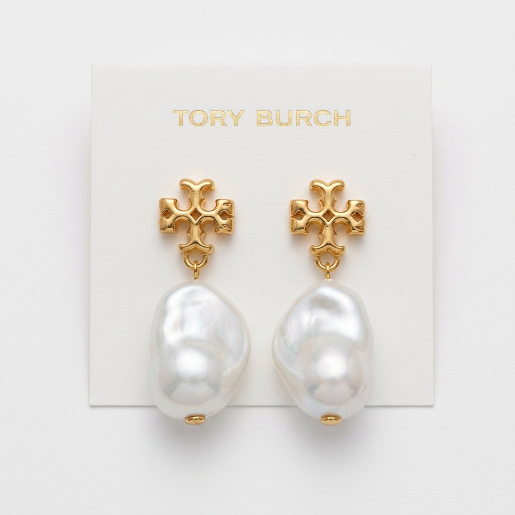 Tory Burch gold-tone cross stud earrings with large baroque white pearls, displayed on a white brand card.