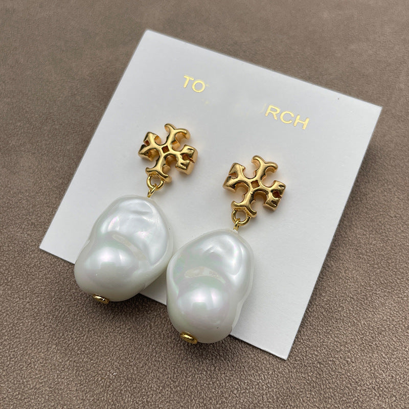 Both earrings displayed face-up on a soft, neutral background (light gray or ivory suede), highlighting the pearl’s luster and gold setting.