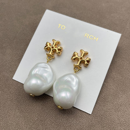 Both earrings displayed face-up on a soft, neutral background (light gray or ivory suede), highlighting the pearl’s luster and gold setting.