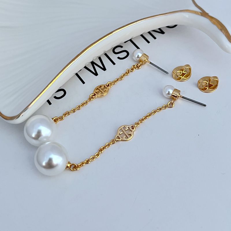 Clean, vertical shot of a single earring against a soft, neutral background, clearly showing the Double T logo above the pearl drop.