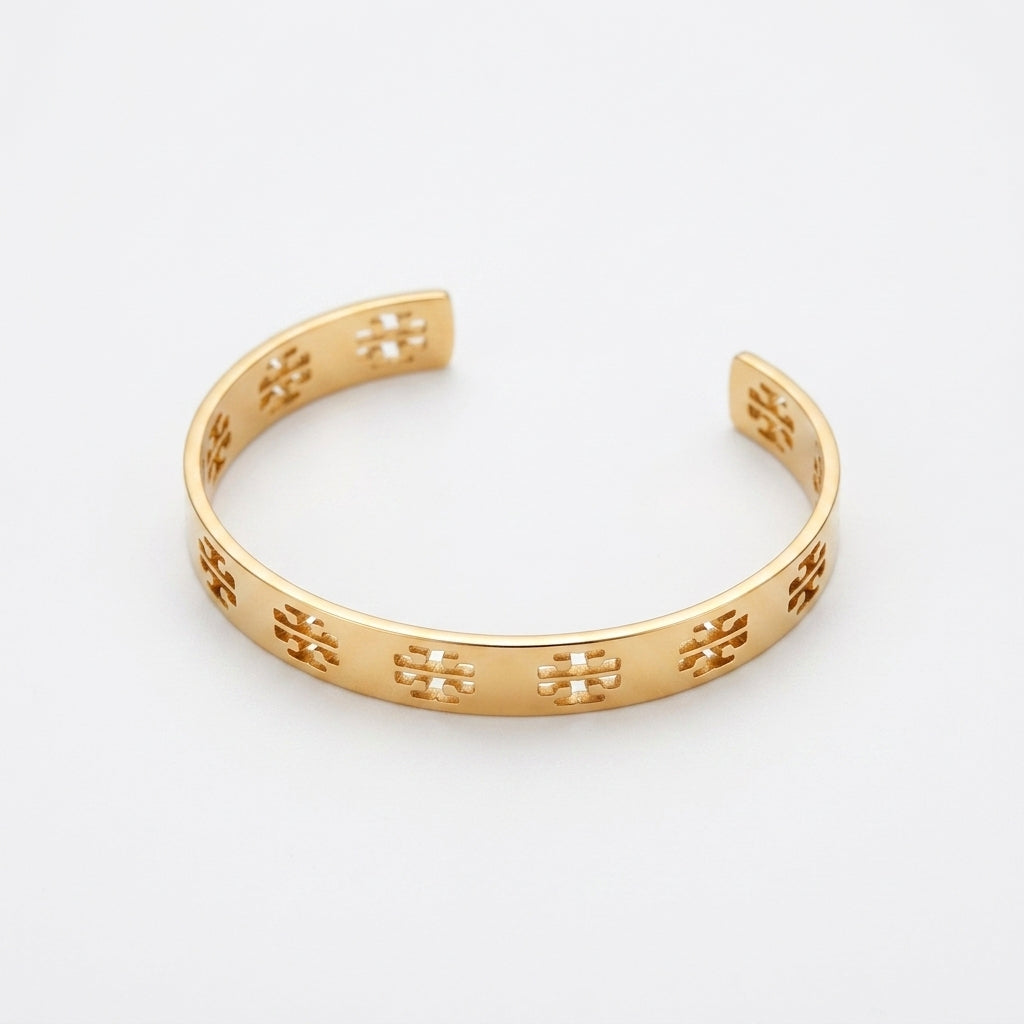 A gold open cuff bracelet featuring a repeating cutout logo pattern, displayed on a clean white background.