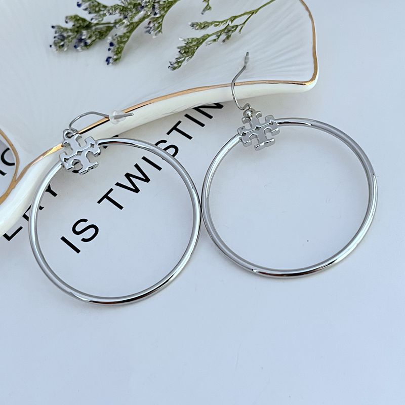 Tory Burch Rose Gold T Logo Hoop Earrings on a neutral background, showcasing the iconic logo and warm rose gold tone."
