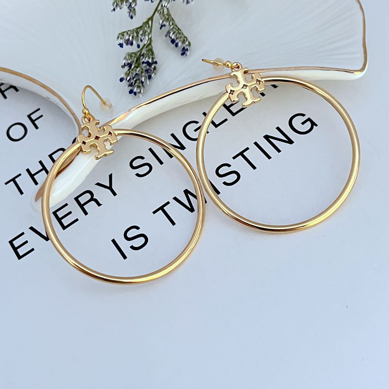 Tory Burch Rose Gold T Logo Hoop Earrings on a neutral background, showcasing the iconic logo and warm rose gold tone."