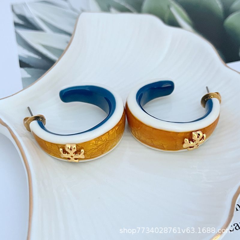 Clean, front-facing shot of a single hoop against a neutral background, clearly displaying the integrated Double T logo on the curve of the rolled gold hoop.