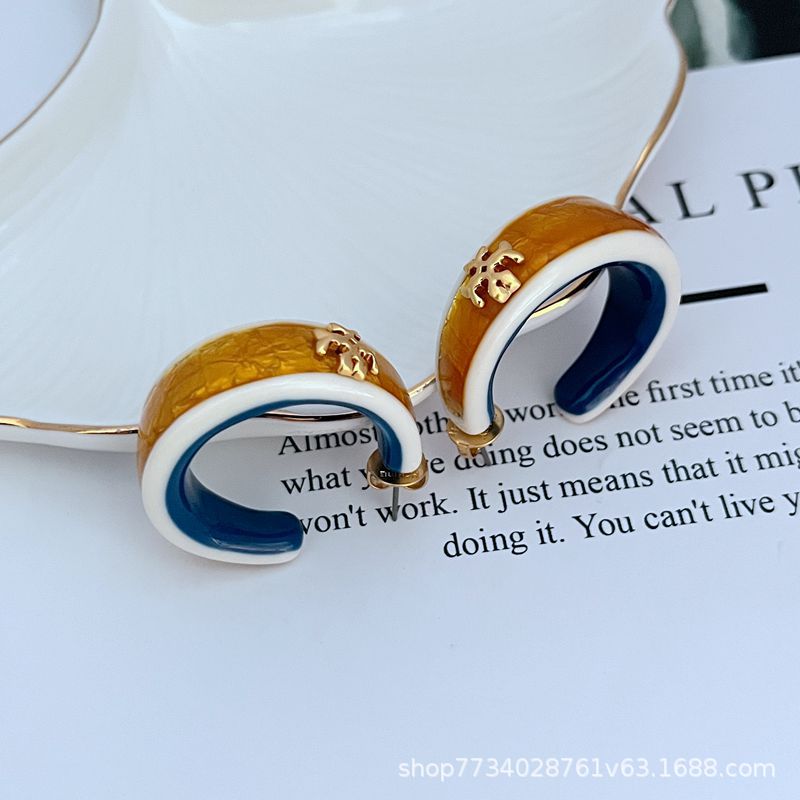 Clean, front-facing shot of a single hoop against a neutral background, clearly displaying the integrated Double T logo on the curve of the rolled gold hoop.