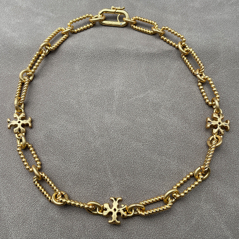 Necklace laid flat on a dark, luxurious background (black velvet or deep navy), highlighting the brilliant contrast between the gold chain and crystal-studded pendant.