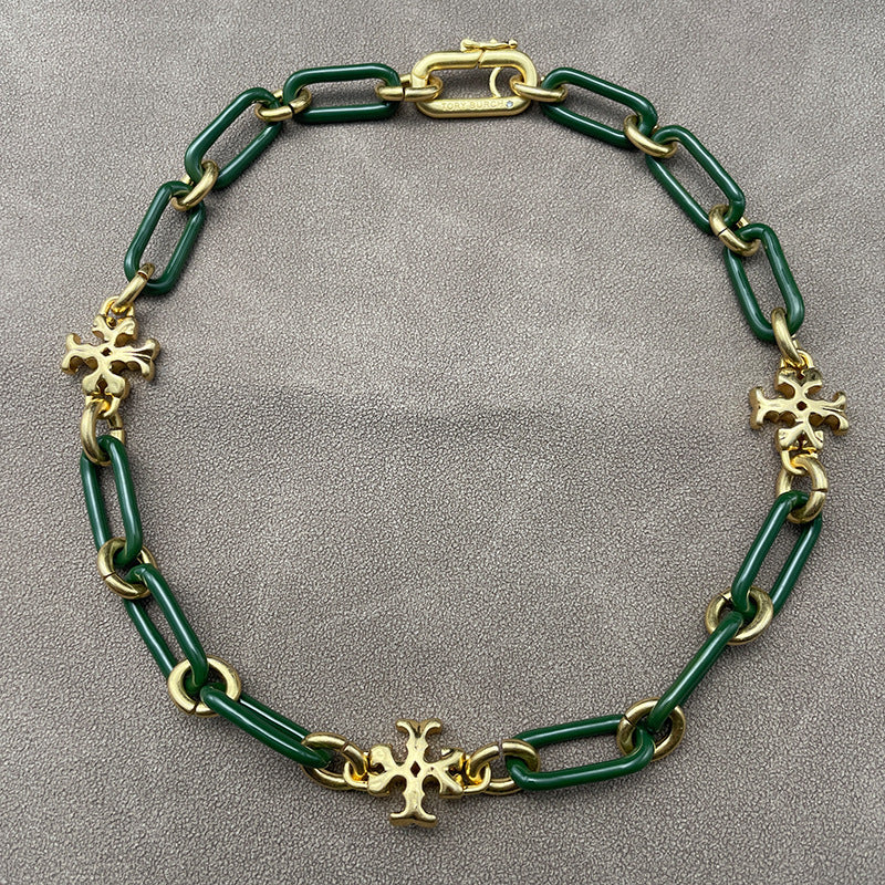 Necklace laid flat on a smooth, light background (white ceramic or pale marble), highlighting the short chain length and pendant detail.
