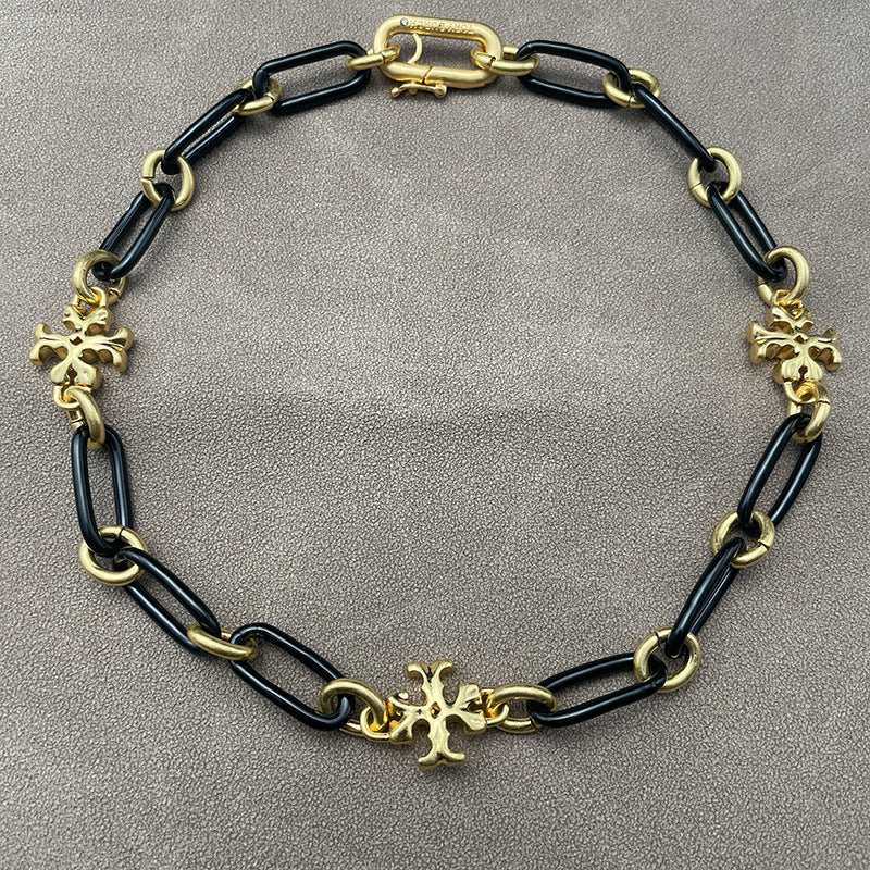 Necklace laid flat on a smooth, light background (white ceramic or pale marble), highlighting the short chain length and pendant detail.