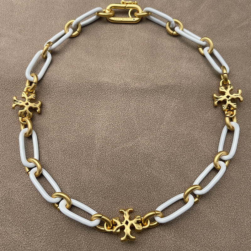 Necklace laid flat on a smooth, light background (white ceramic or pale marble), highlighting the short chain length and pendant detail.