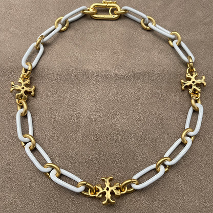 Necklace laid flat on a smooth, light background (white ceramic or pale marble), highlighting the short chain length and pendant detail.