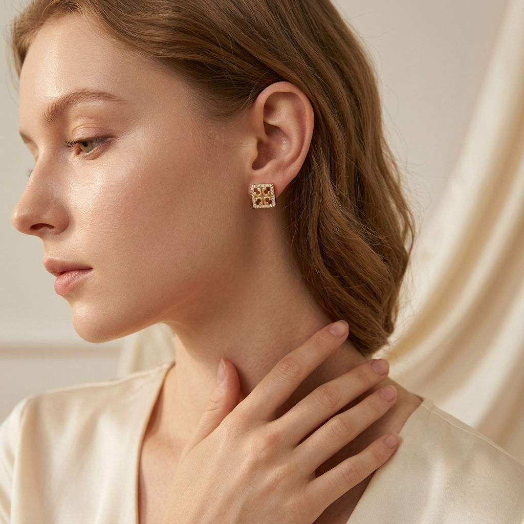 Close-up of a woman wearing gold earrings with a neutral background