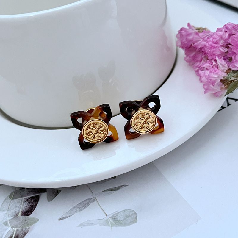 A curated flat-lay showing multiple pieces (e.g., earrings and a necklace) against a clean, light background, highlighting the beautiful tortoise shell pattern and gold logo details.