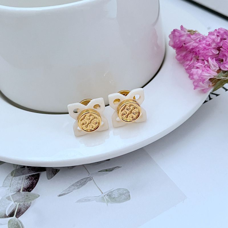 A curated flat-lay showing multiple pieces (e.g., earrings and a necklace) against a clean, light background, highlighting the beautiful tortoise shell pattern and gold logo details.