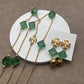 Flat lay of multiple pieces (e.g., earrings and a pendant) arranged on a neutral linen background, highlighting the contrast between tortoiseshell texture and gold metal.