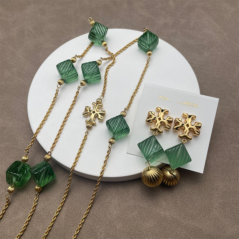 Flat lay of multiple pieces (e.g., earrings and a pendant) arranged on a neutral linen background, highlighting the contrast between tortoiseshell texture and gold metal.