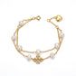 A gold-tone double-strand chain bracelet featuring white freshwater pearls, a central pavé cross charm, and an adjustable heart-shaped clasp, shown on a plain white background.