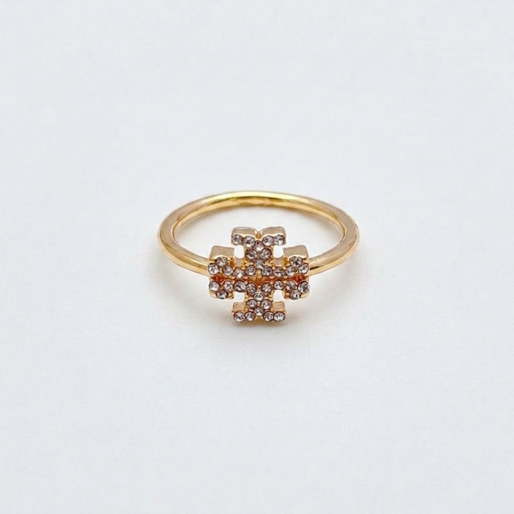 A gold ring with a central geometric cluster of small clear stones, photographed on a plain light background.
