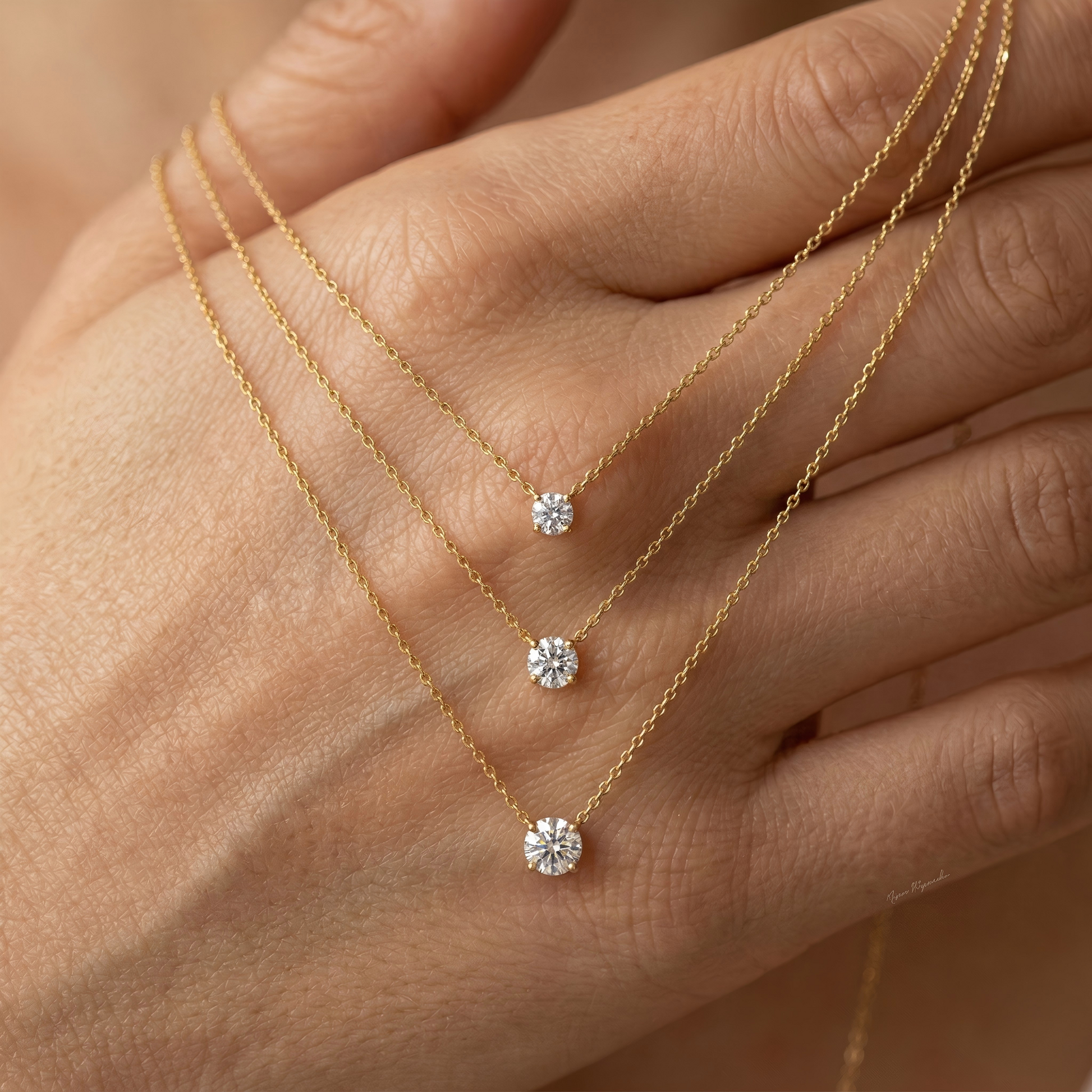 Close-up of a hand gently holding the necklace, fingers wearing matching rings, soft blurred white fabric background, natural skin texture, showing scale and intimate jewelry interaction.