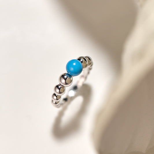 Silver ring with a blue bead on a light background