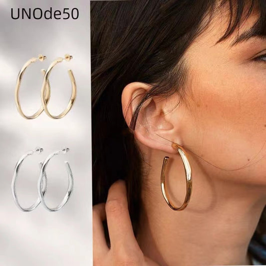 Gold hoops on neutral or warm background. Alt: “UNO de 50 Gold Twisted Hoop Earrings – Textured Gold Hoops.”
