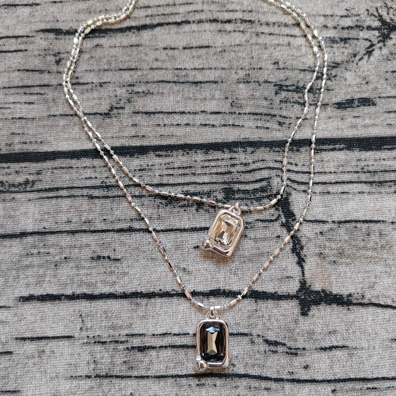 Multi-strand necklace displayed with crystals catching light. Alt: “UNO de 50 Multi-Strand Pendant Chain Necklace with Crystals.”