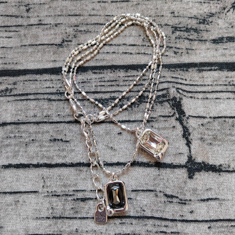 Multi-strand necklace displayed with crystals catching light. Alt: “UNO de 50 Multi-Strand Pendant Chain Necklace with Crystals.”
