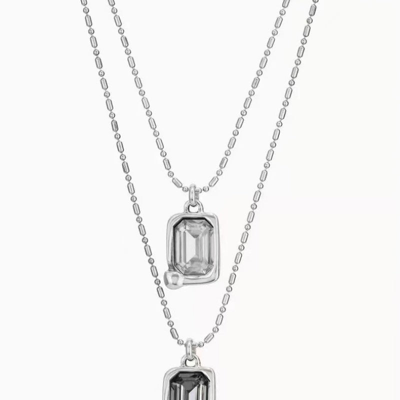 Multi-strand necklace displayed with crystals catching light. Alt: “UNO de 50 Multi-Strand Pendant Chain Necklace with Crystals.”