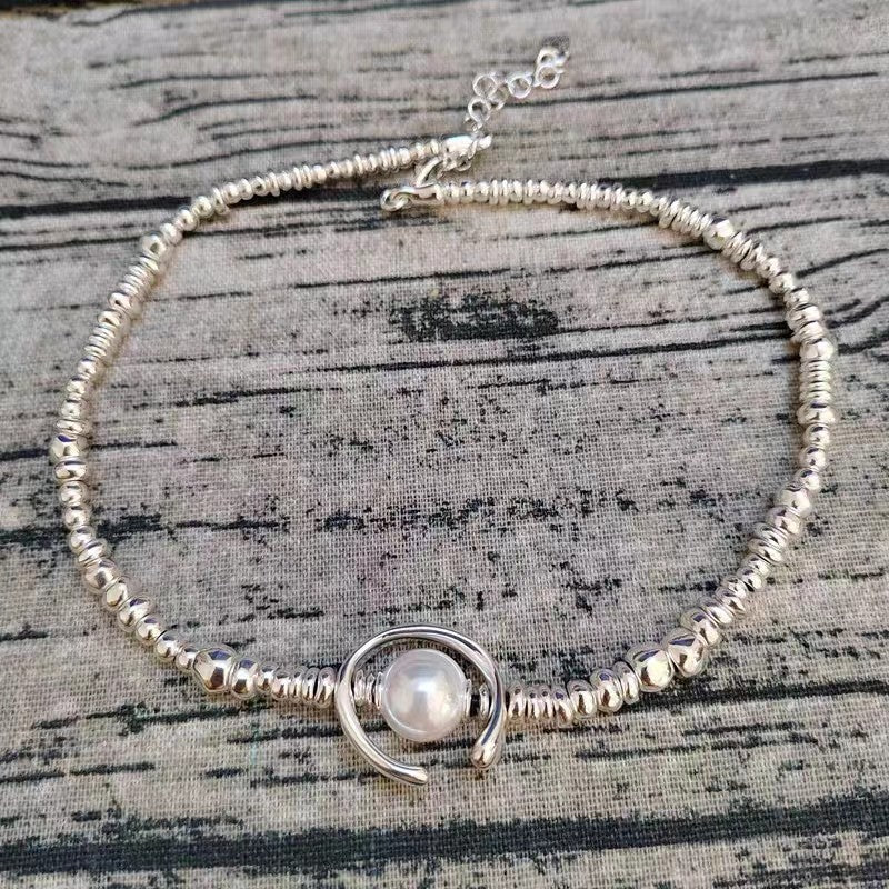 Short necklace on neutral background, pearl centered. Alt: “UNO de 50 Short Beaded Necklace with Pearl.”