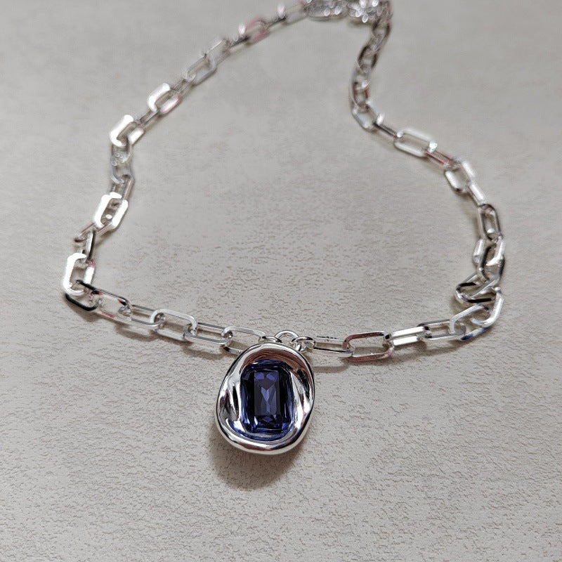  Necklace on neutral or jewel-tone background. Alt: “UNO de 50 Short Link Chain Pendant Necklace with Purple Crystal.”