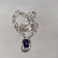  Necklace on neutral or jewel-tone background. Alt: “UNO de 50 Short Link Chain Pendant Necklace with Purple Crystal.”