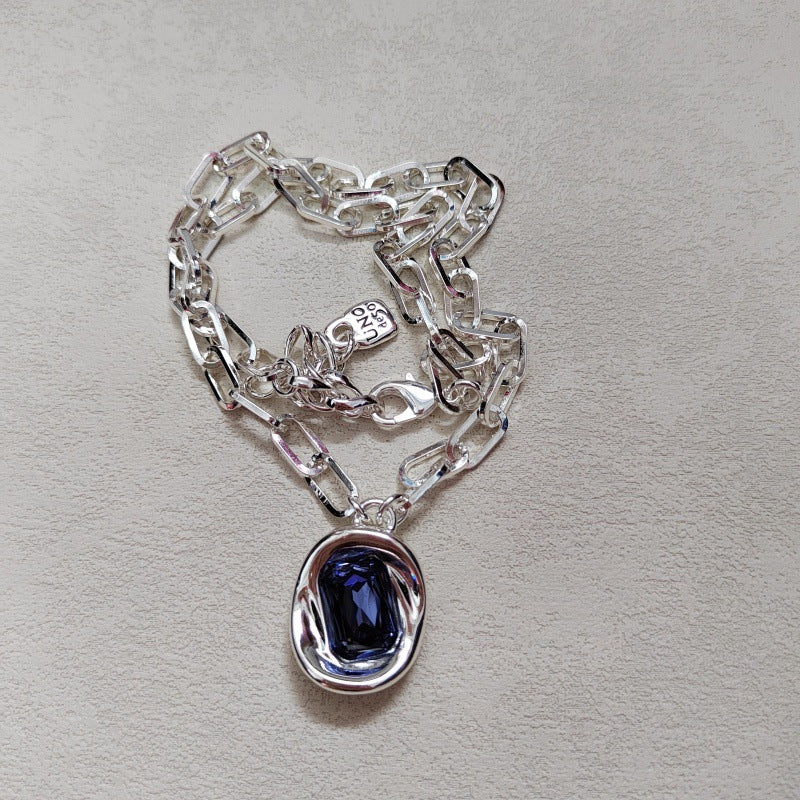  Necklace on neutral or jewel-tone background. Alt: “UNO de 50 Short Link Chain Pendant Necklace with Purple Crystal.”