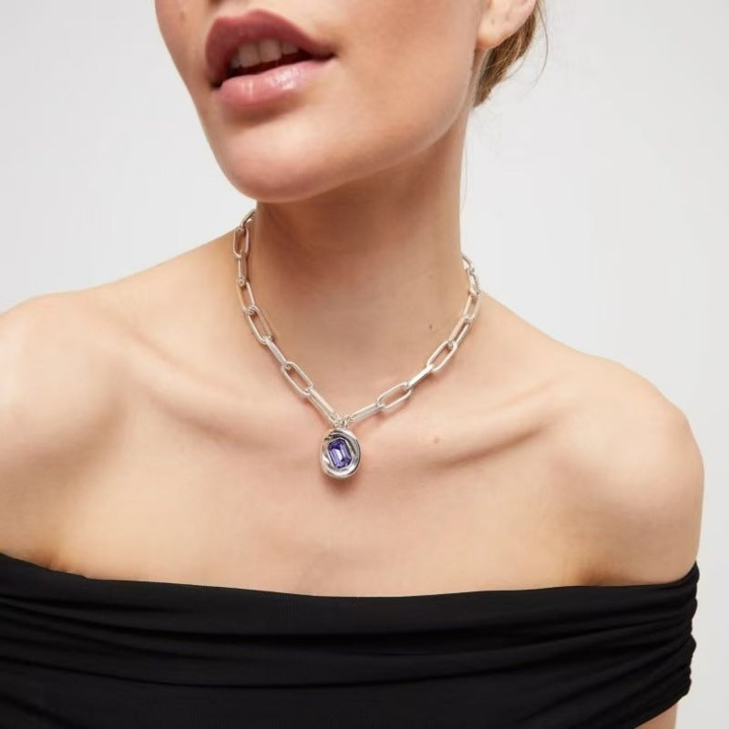  Necklace on neutral or jewel-tone background. Alt: “UNO de 50 Short Link Chain Pendant Necklace with Purple Crystal.”