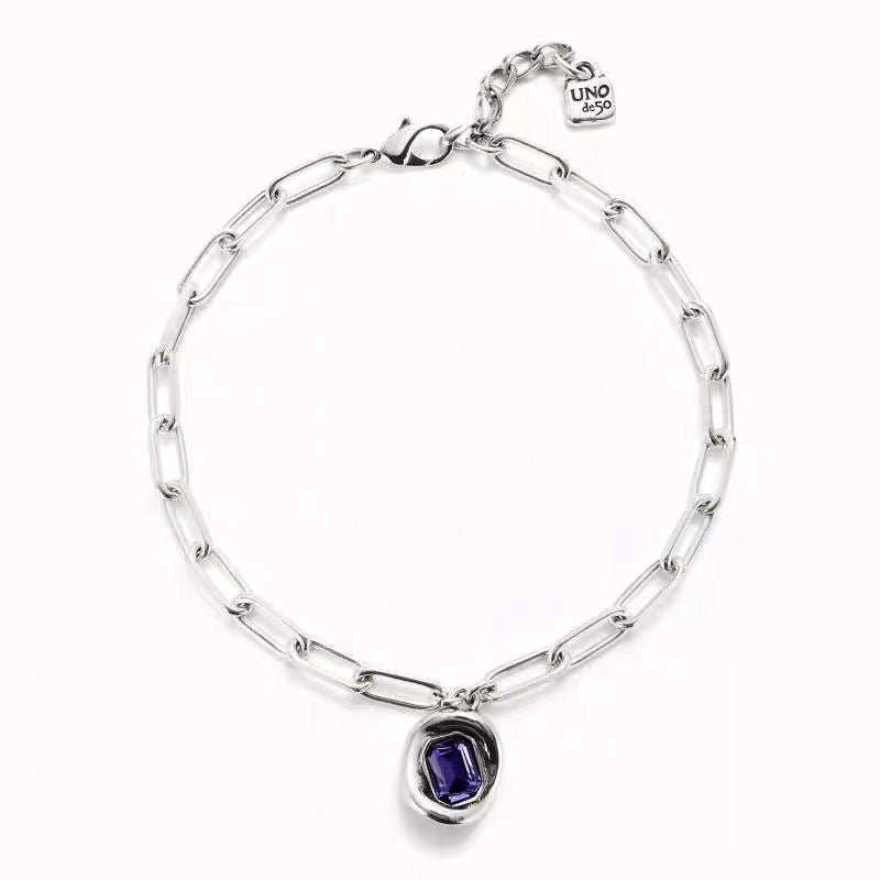  Necklace on neutral or jewel-tone background. Alt: “UNO de 50 Short Link Chain Pendant Necklace with Purple Crystal.”