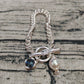 Necklace on neutral background showing central clasp. Alt: “UNO de 50 Short Necklace with Central Clasp.”