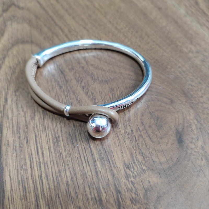 Silver bracelet with a round silver charm on a wooden surface