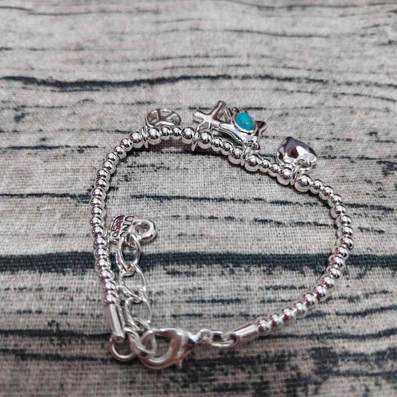 Silver bracelet with various charms on a textured surface