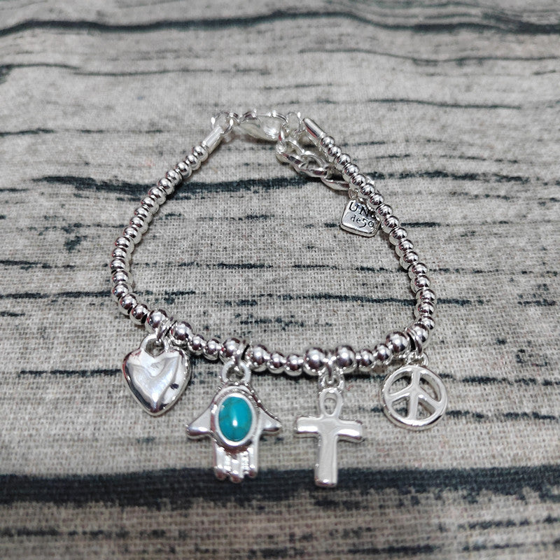 Silver bracelet with various charms on a textured surface