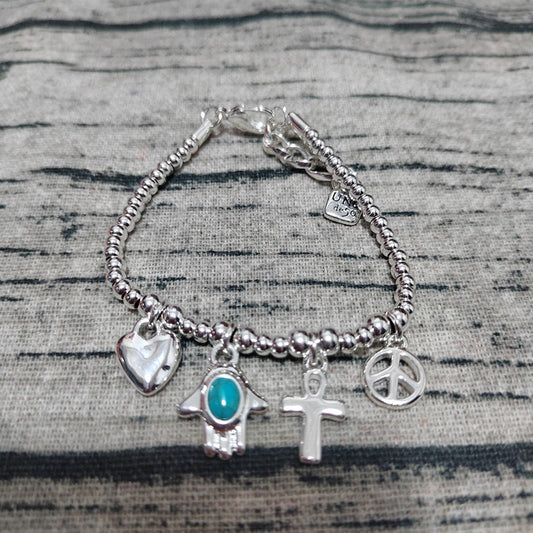 Silver bracelet with various charms on a textured surface