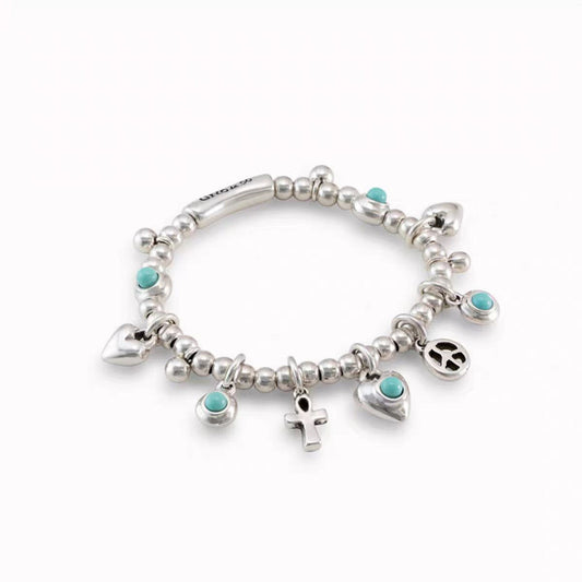A sterling silver charm bracelet with small round beads, turquoise stone accents, and multiple dangling charms including hearts, an anchor, a peace sign, and a small cross, shown on a plain white background.