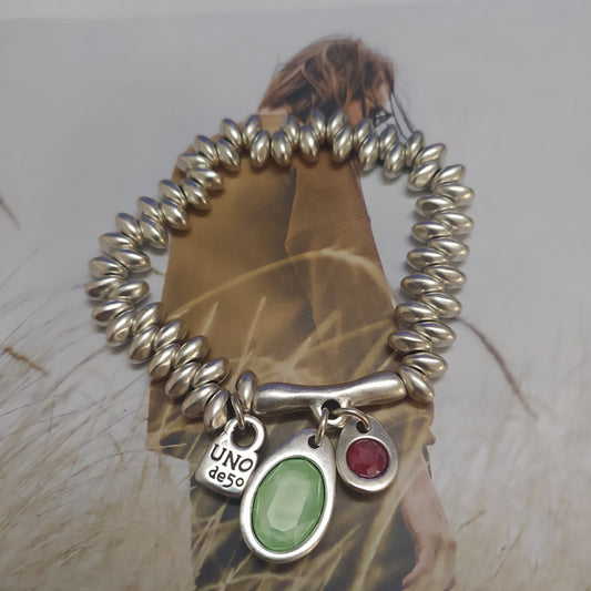 Bracelet on neutral background. Alt: “UNOde50 Bracelet with Blue Crystal Charms.”