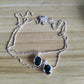 A silver beaded chain necklace with two dangling teardrop-shaped dark green iridescent gemstone pendants, displayed on a light wood grain surface.
