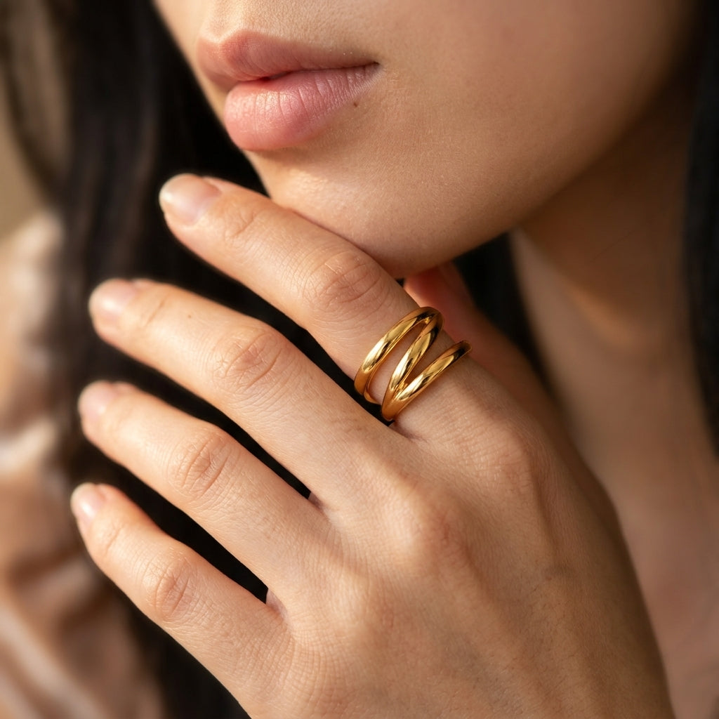 A close-up of a person's hand wearing a double-band gold ring, with the lips of the same person visible in the frame.