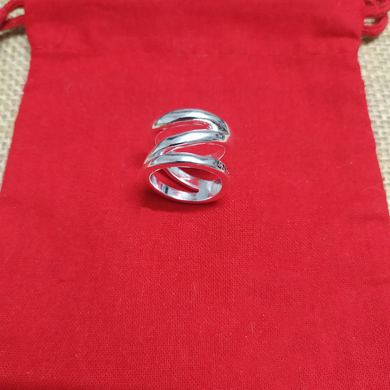 A polished silver ring with a multi-layered, wavy spiral design, displayed on a textured red fabric pouch.