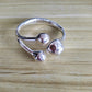 A polished silver-toned open cuff ring with three rounded bead-like protrusions, photographed on a light wood surface.
