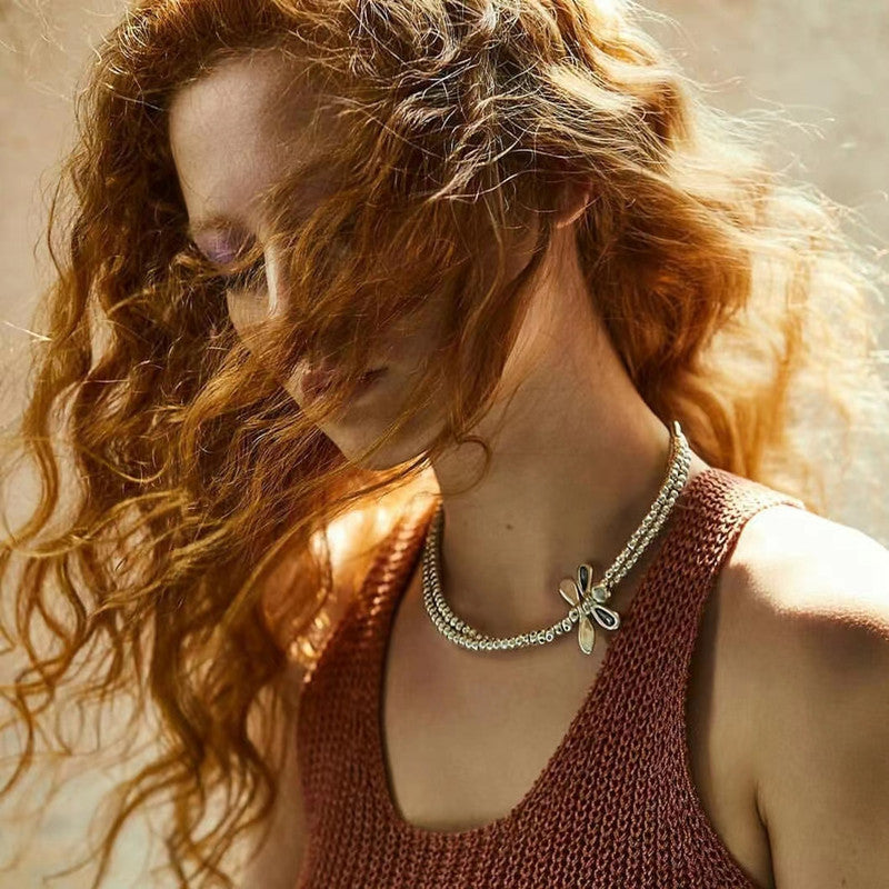 Woman with flowing hair wearing a necklace with a butterfly pendant.
