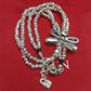 Silver beaded necklace with dragonfly and heart charm on a red background
