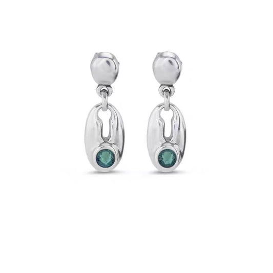 A pair of silver dangle earrings with a polished oval drop and a small round green gemstone at the bottom, set against a plain white background.