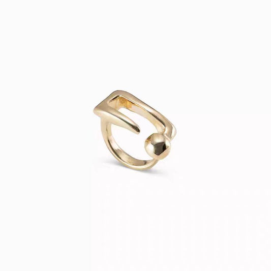 A gold-plated metal ring with a unique, abstract open design featuring a small polished ball accent, shown on a clean white background.