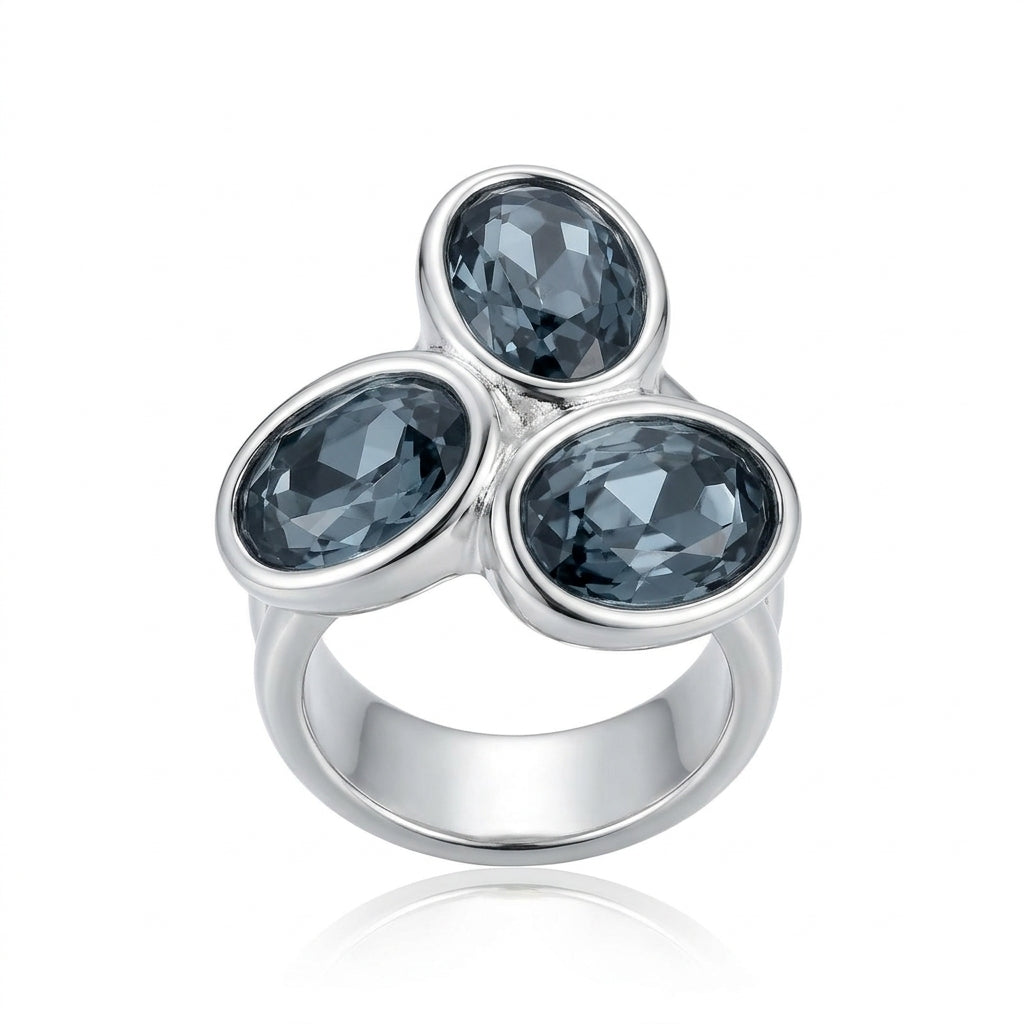 A silver ring featuring three faceted oval dark gray gemstones arranged in a triangular cluster on a polished silver band, set against a plain white background with a soft reflection.