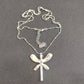 A sterling silver dragonfly pendant necklace with a delicate ball chain, displayed on a dark gray textured background.